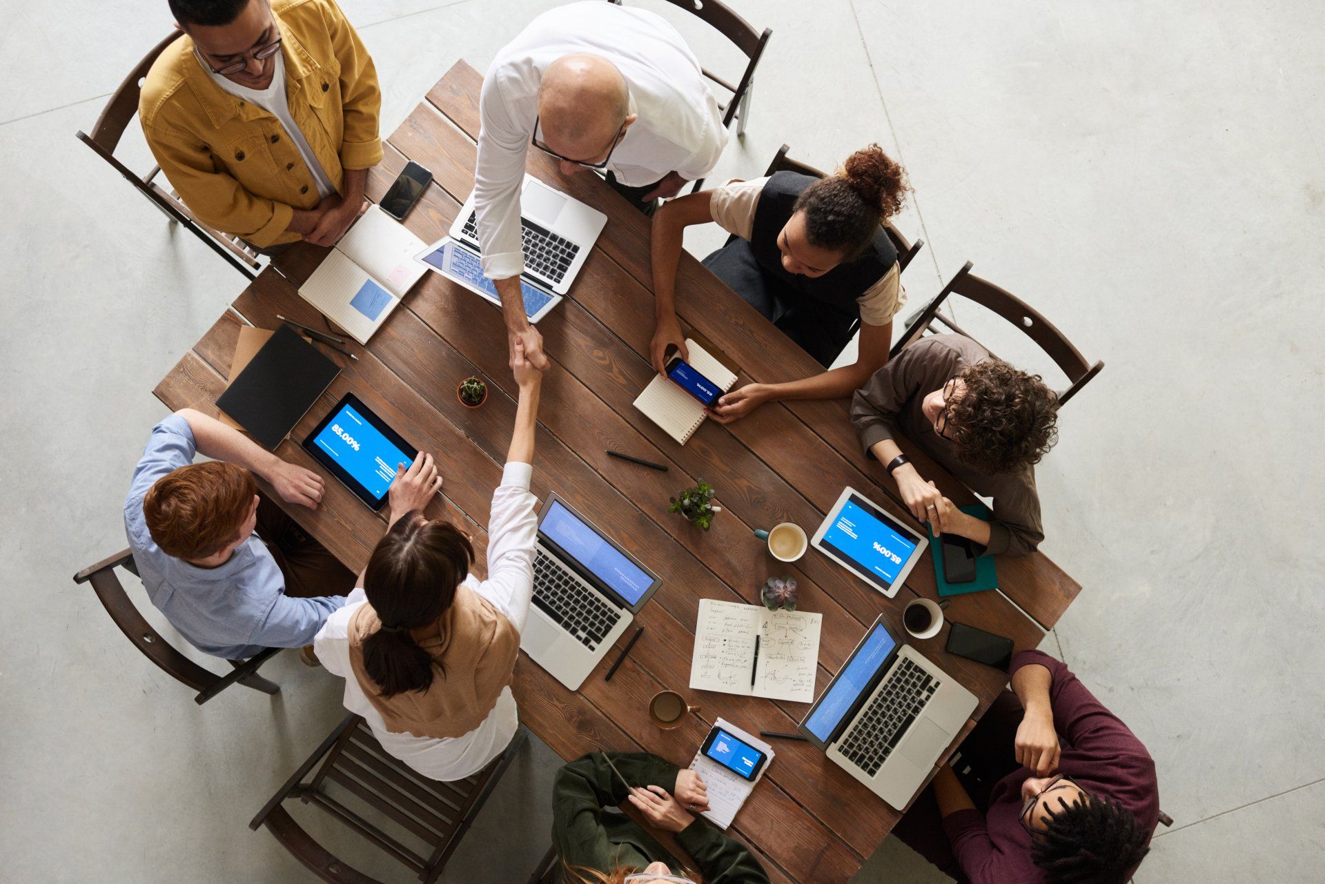 An overhead view of people collaborating around a table with laptops and notes
